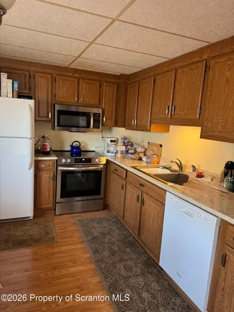a open kitchen with stainless steel appliances granite countertop a sink dishwasher and a stove with wooden floor