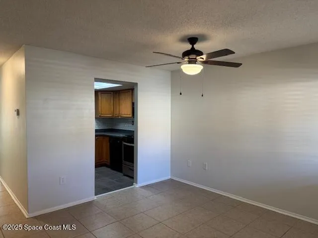 a view of an empty room with a ceiling fan and kitchen view