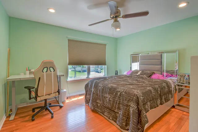 a bedroom with a bed a desk and chair with wooden floor