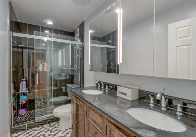 a bathroom with a granite countertop sink a toilet and shower