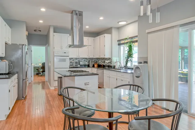 a kitchen with stainless steel appliances granite countertop a stove a sink a refrigerator dining table and chairs