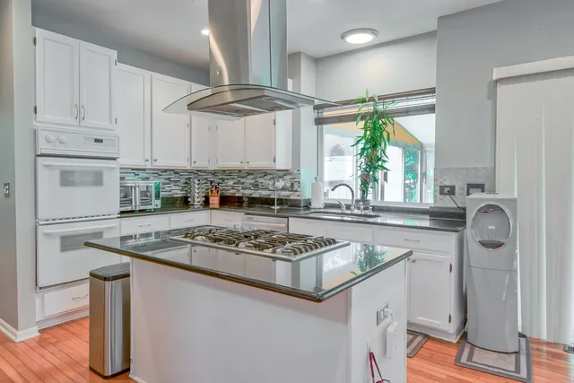a kitchen with stainless steel appliances granite countertop a stove a sink dishwasher and cabinets with wooden floor