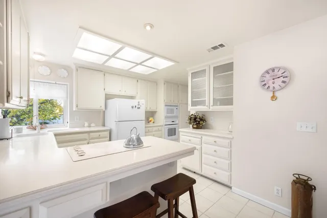 a kitchen with a sink white cabinets and appliances
