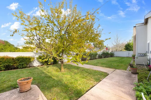 a backyard of a house with table and chairs and potted plants