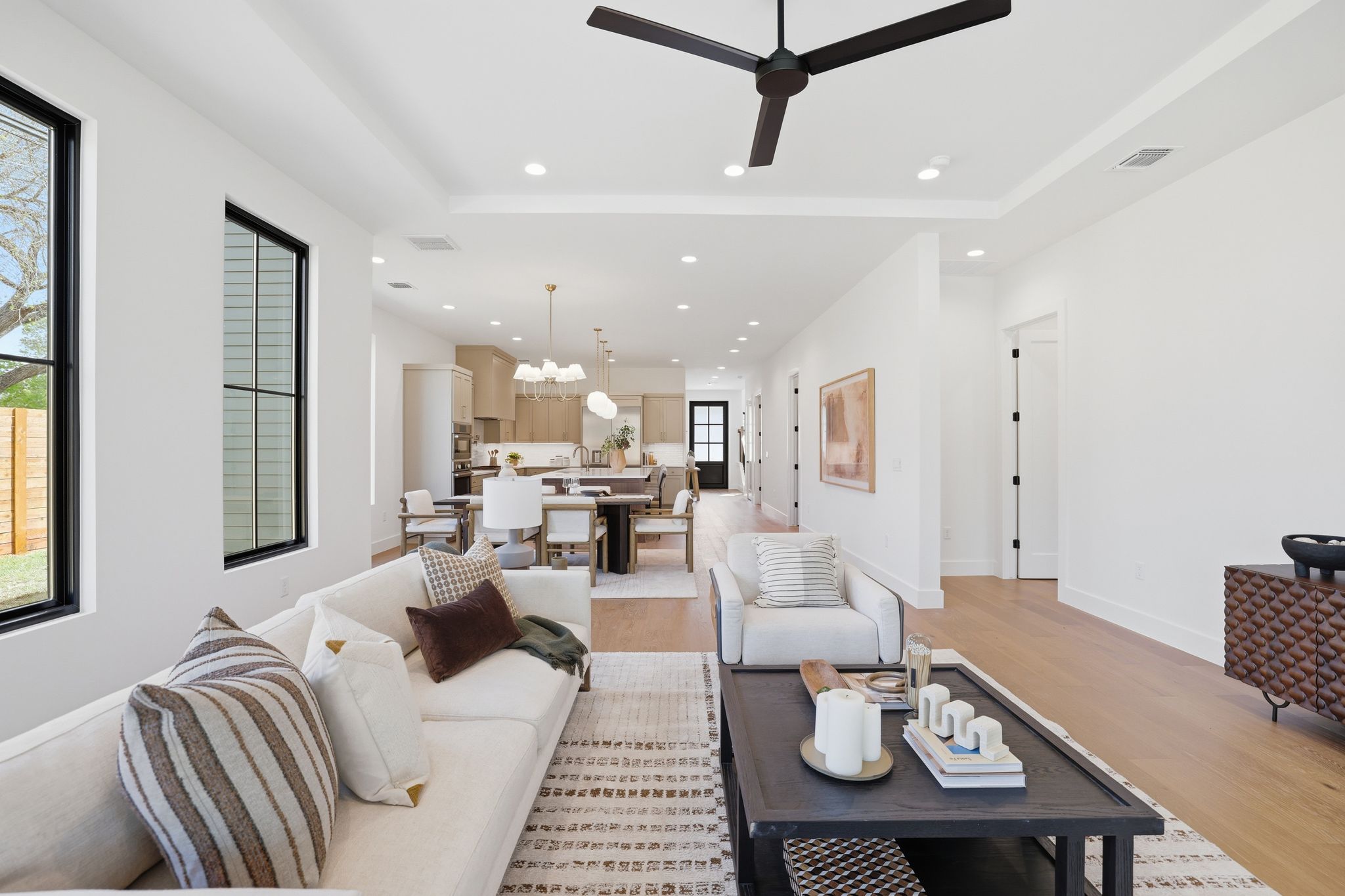 4500 Jinx Avenue Austin, TX 78745 - Photo 21 of 40 Living room featuring a tray ceiling, light wood-type flooring, a ceiling fan, and a chandelier