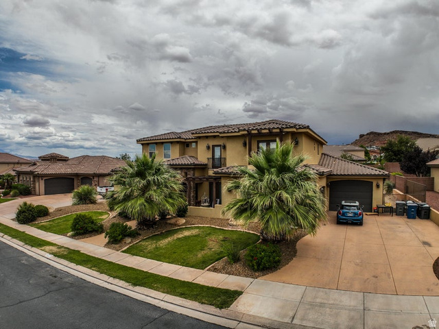 3683 South 2640 West St. George, UT 84790 - Photo 2 of 41 Stucco exterior with a tile roof, featuring a two-car garage, mature palm trees, and a decorative pergola