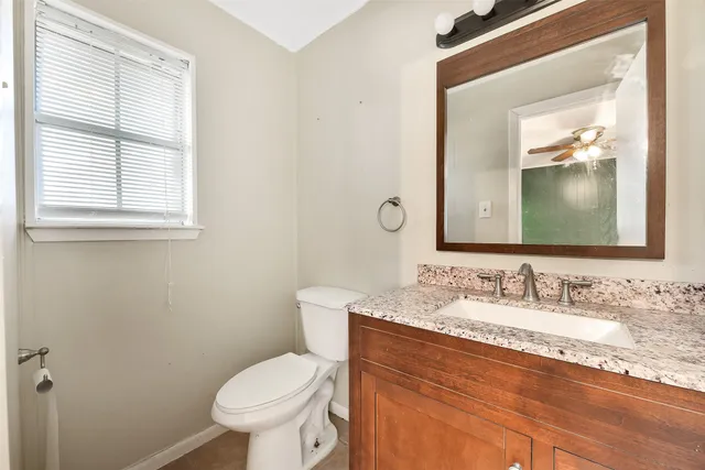a bathroom with a granite countertop toilet sink and mirror