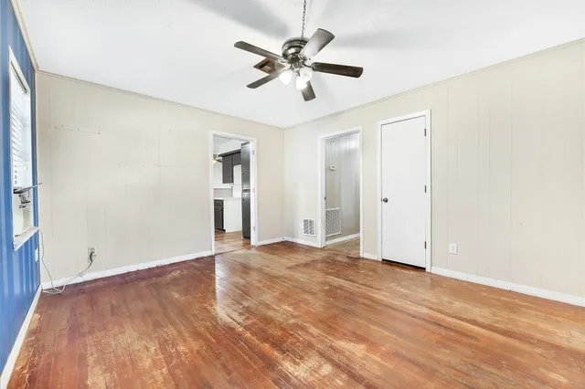 an empty room with wooden floor and ceiling fan