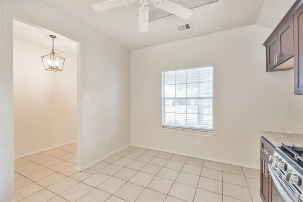 a view of an empty room with window and chandelier fan