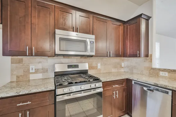 a kitchen with granite countertop cabinets stainless steel appliances and a counter space