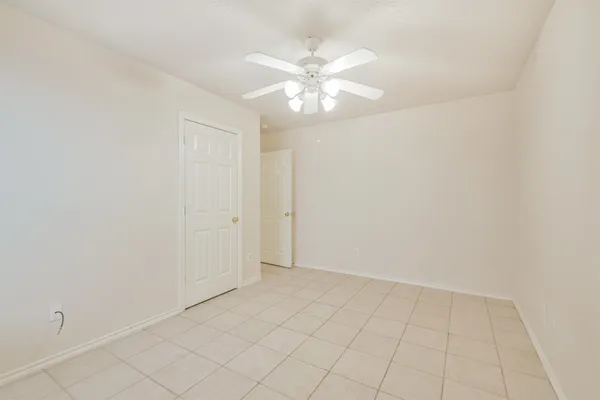 an empty room with white walls and chandelier fan