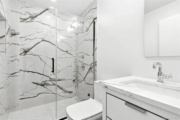 a bathroom with a granite countertop sink and a toilet