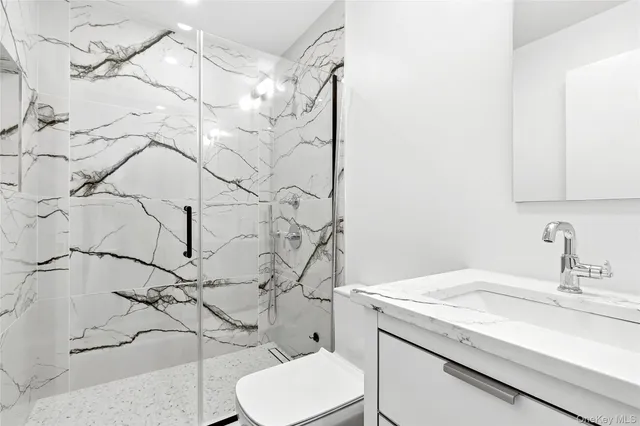 a bathroom with a granite countertop sink and a toilet