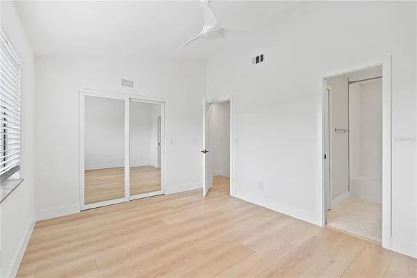 a view of an empty room with wooden floor and closet
