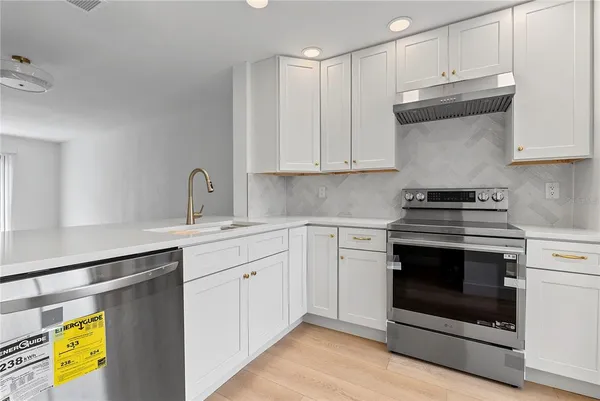 a kitchen with stainless steel appliances granite countertop a stove a sink and a white cabinets
