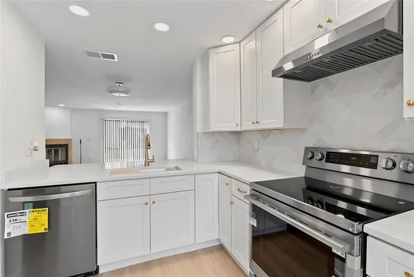 a kitchen with stainless steel appliances white cabinets and a stove top oven