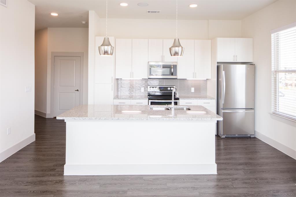 2101 West Rosedale Street, Unit 308 Fort Worth, TX 76104 - Photo 5 of 8 a view of a kitchen with stainless steel appliances a refrigerator and a stove top oven