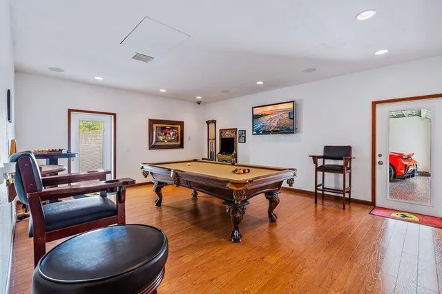 a living room with furniture pool table and wooden floor