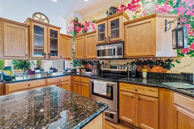 a kitchen with granite countertop lots of wooden cabinets and stainless steel appliances