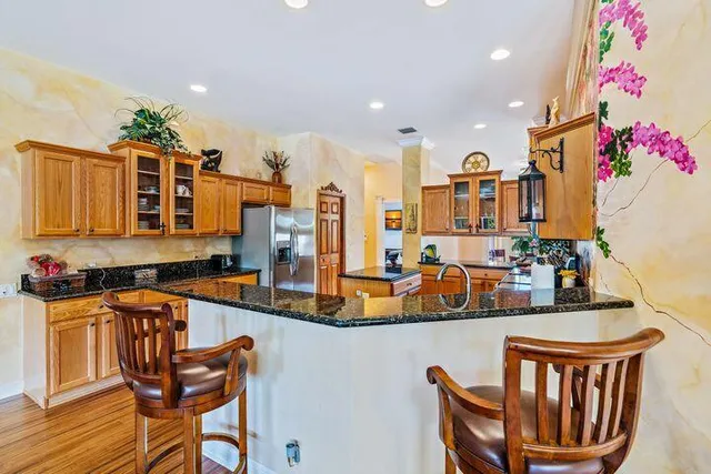 a dining hall with stainless steel appliances granite countertop a kitchen island a stove a dining table and chairs with wooden floor