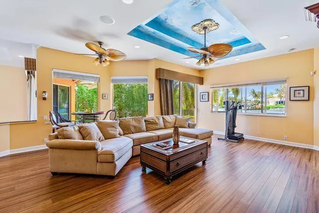 a living room with furniture a ceiling fan and a large window
