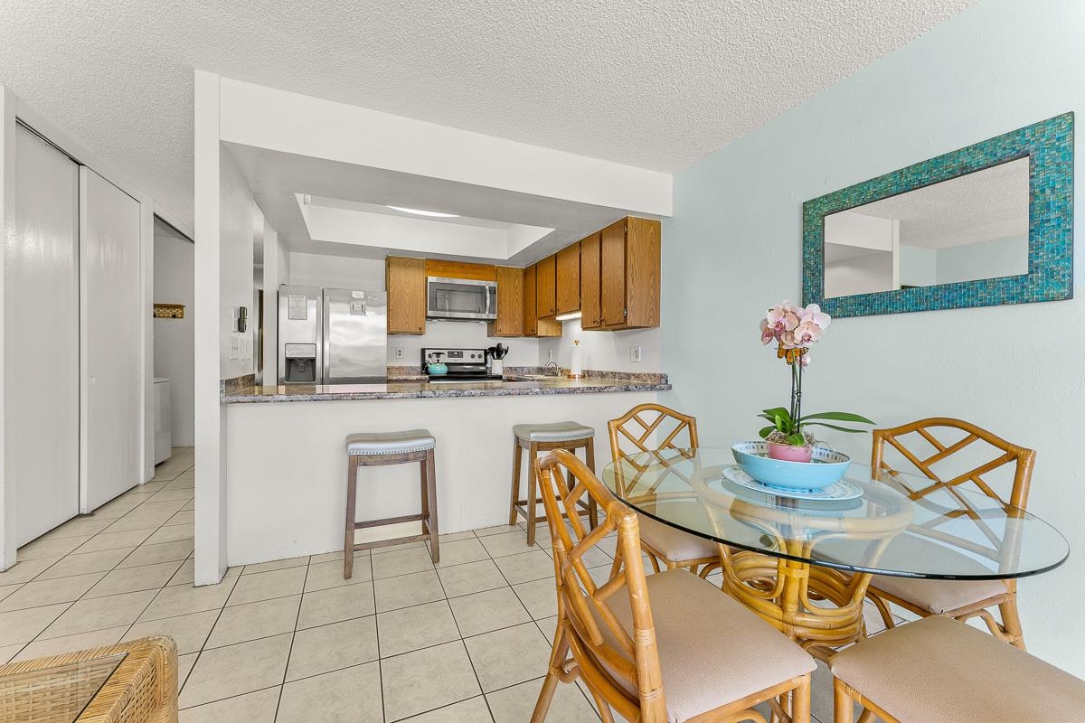 940 South Kihei Road, Unit B204 Kihei, HI 96753 - Photo 9 of 30 a kitchen with stainless steel appliances granite countertop a sink a stove a dining table and chairs