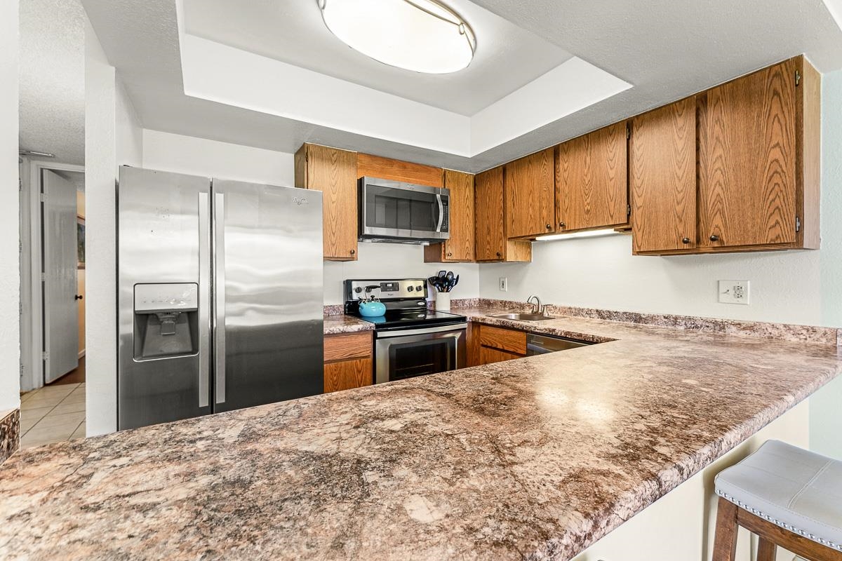 940 South Kihei Road, Unit B204 Kihei, HI 96753 - Photo 10 of 30 a kitchen with granite countertop a refrigerator and a stove top oven