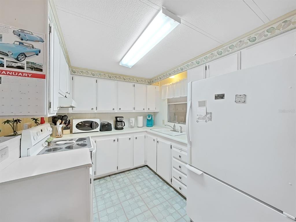 12501 Ulmerton Road, Unit 140 Largo, FL 33774 - Photo 8 of 20 a kitchen with white cabinets and white appliances