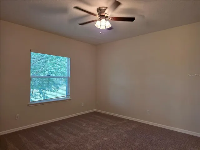 an empty room with a window and a fan