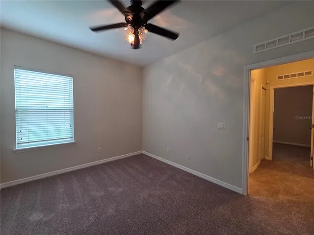 an empty room with a window and a fan