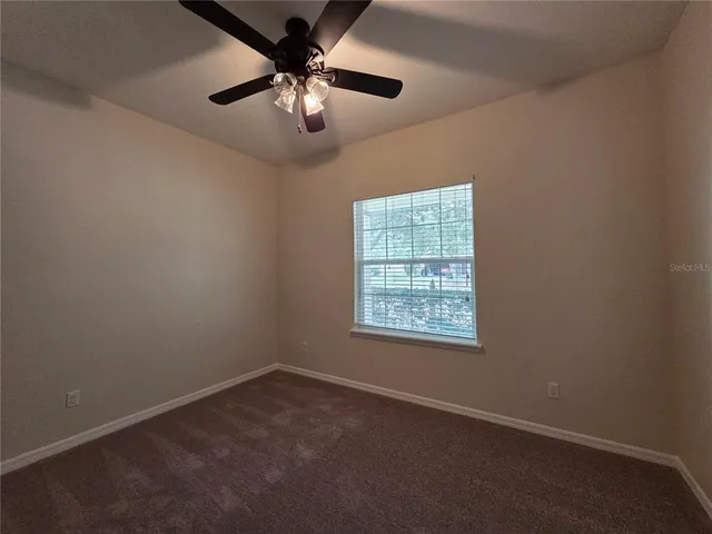 an empty room with a chandelier fan and windows