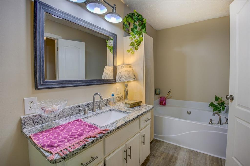 2100 Morgan Lane Covington, GA 30014 - Photo 33 of 47 a bathroom with a granite countertop tub a sink and a mirror