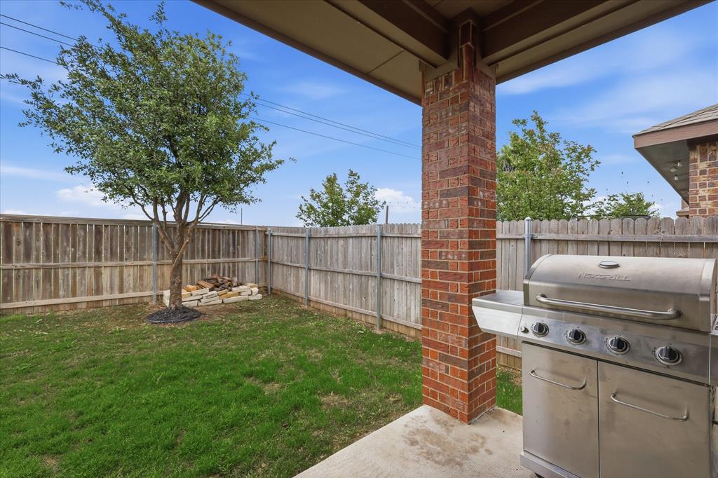 11500 Starlight Ranch Fort Worth, TX 76052 - Photo 32 of 40 This property features a covered patio with a brick pillar, overlooking a fenced yard with a mature tree and a lush lawn