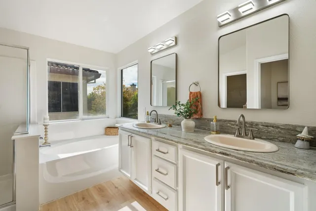 a bathroom with a tub a double vanity sink and mirror