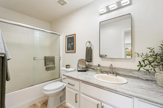 a bathroom with a granite countertop sink toilet and mirror