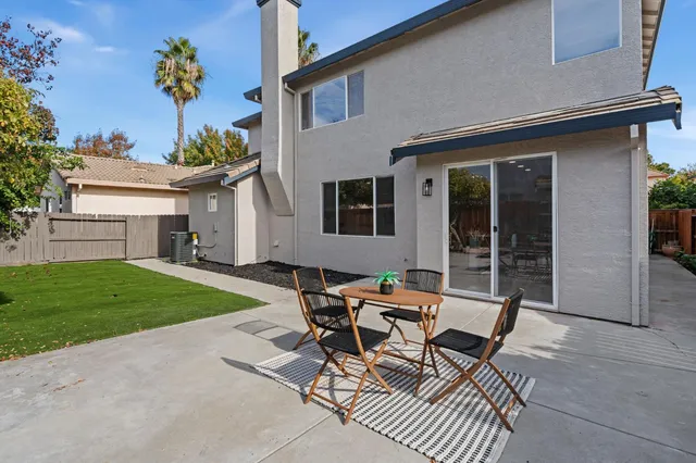 a patio with table and chairs and potted plants