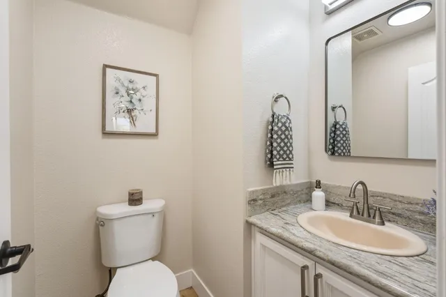 a bathroom with a granite countertop toilet sink and mirror