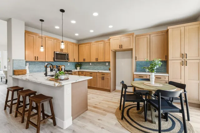 a kitchen with kitchen island a stove a table and chairs in it