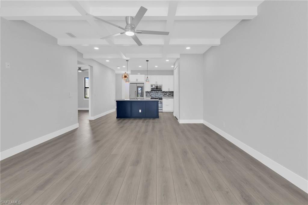 1323 Wesley Drive Punta Gorda, FL 33950 - Photo 15 of 50 an empty room with wooden floor ceiling fan and kitchen view