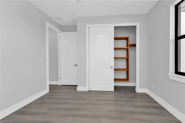 a view of an empty room with closet and wooden floor