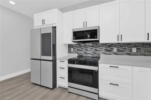 a kitchen with cabinets stainless steel appliances and wooden floor