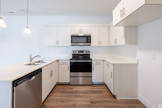 675 West 4500th South, Unit P302 Mapleton, UT 84664 - Photo 11 of 16 Modern kitchen with white cabinetry, stainless steel appliances, light-toned countertops, wood-finish flooring, and pendant lighting