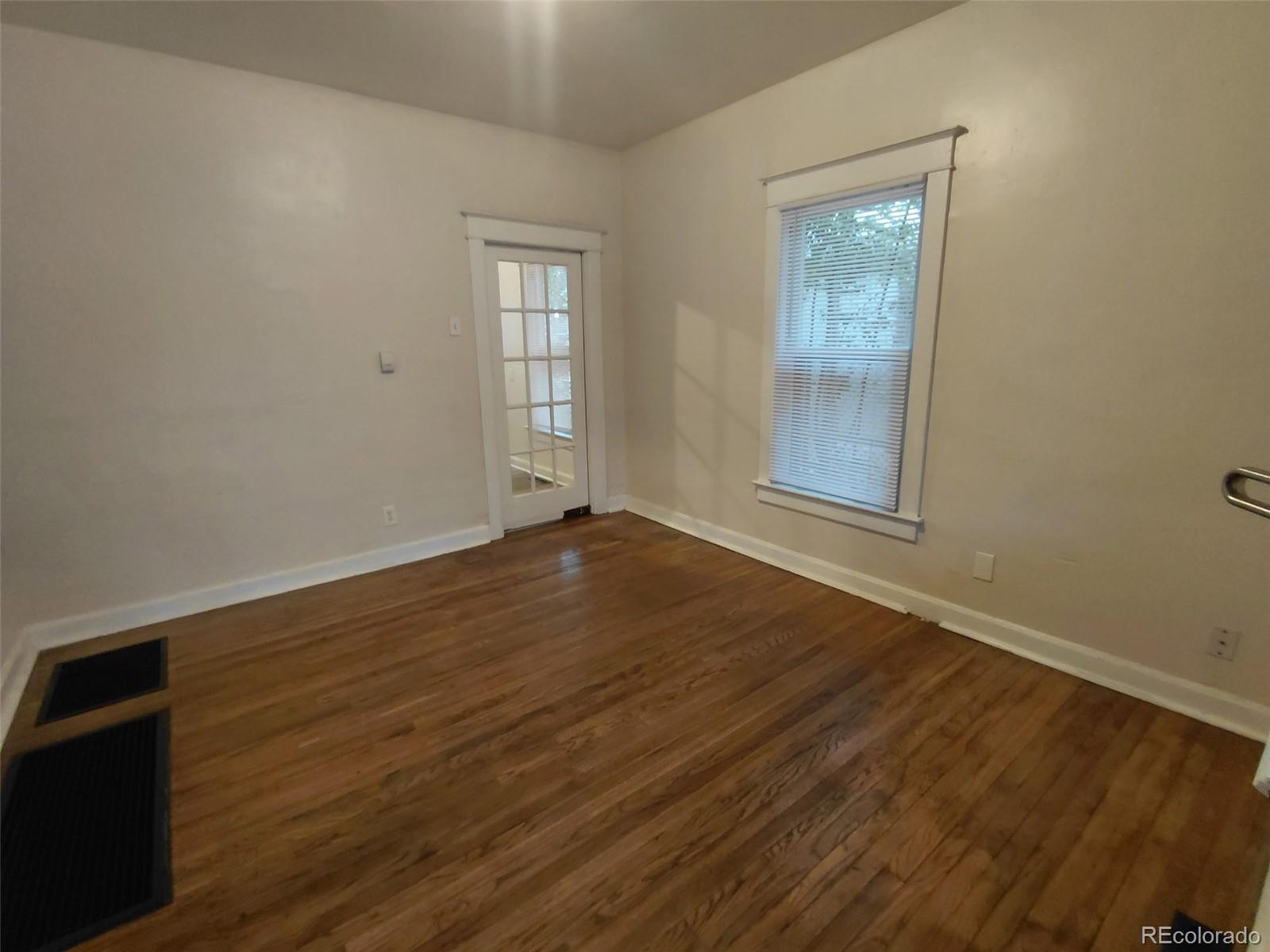 1917 South Fox Street Denver, CO 80223 - Photo 2 of 10 an empty room with wooden floor and windows