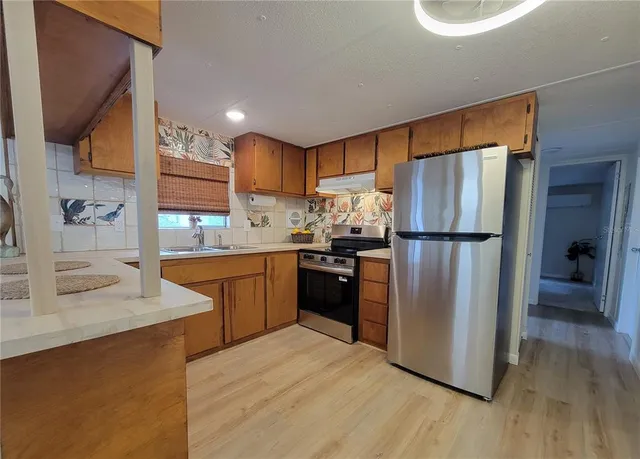 a kitchen with stainless steel appliances granite countertop a refrigerator a sink and a stove
