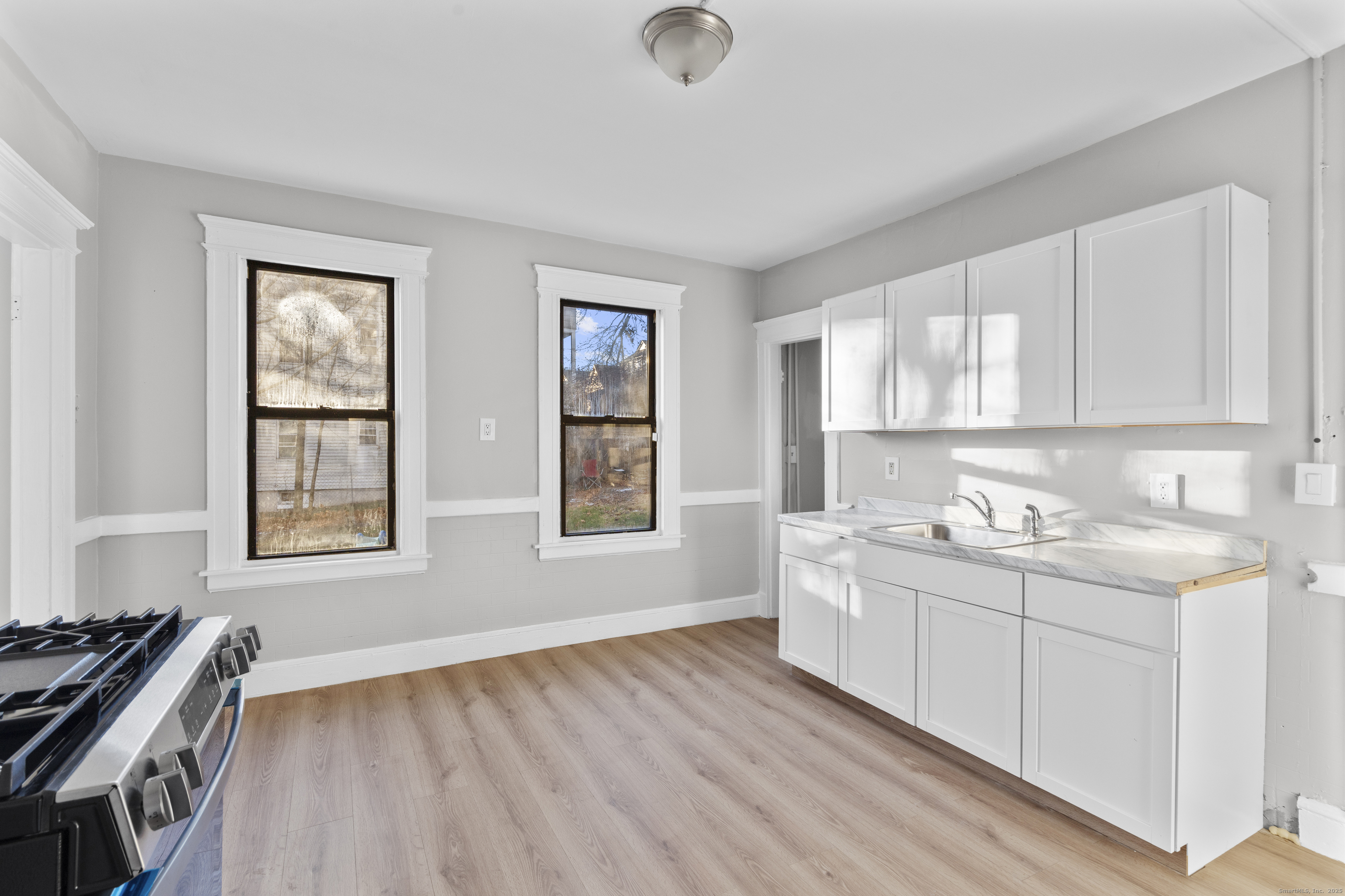 141 Draher Street Waterbury, CT 06708 - Photo 11 of 20 a kitchen with stainless steel appliances granite countertop a stove a sink and white cabinets with wooden floor