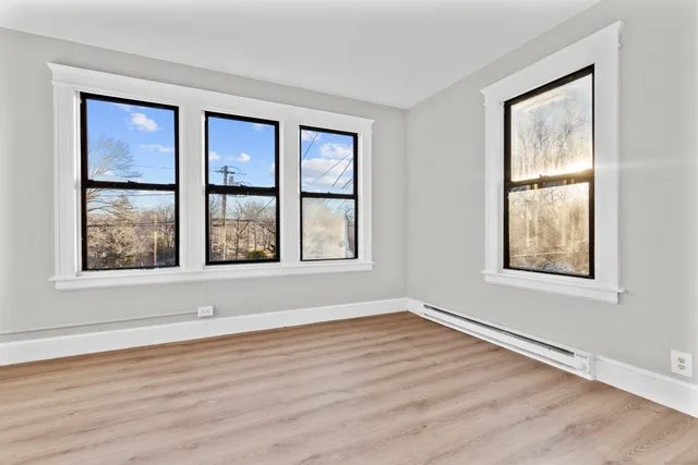 a view of an empty room with wooden floor and a window