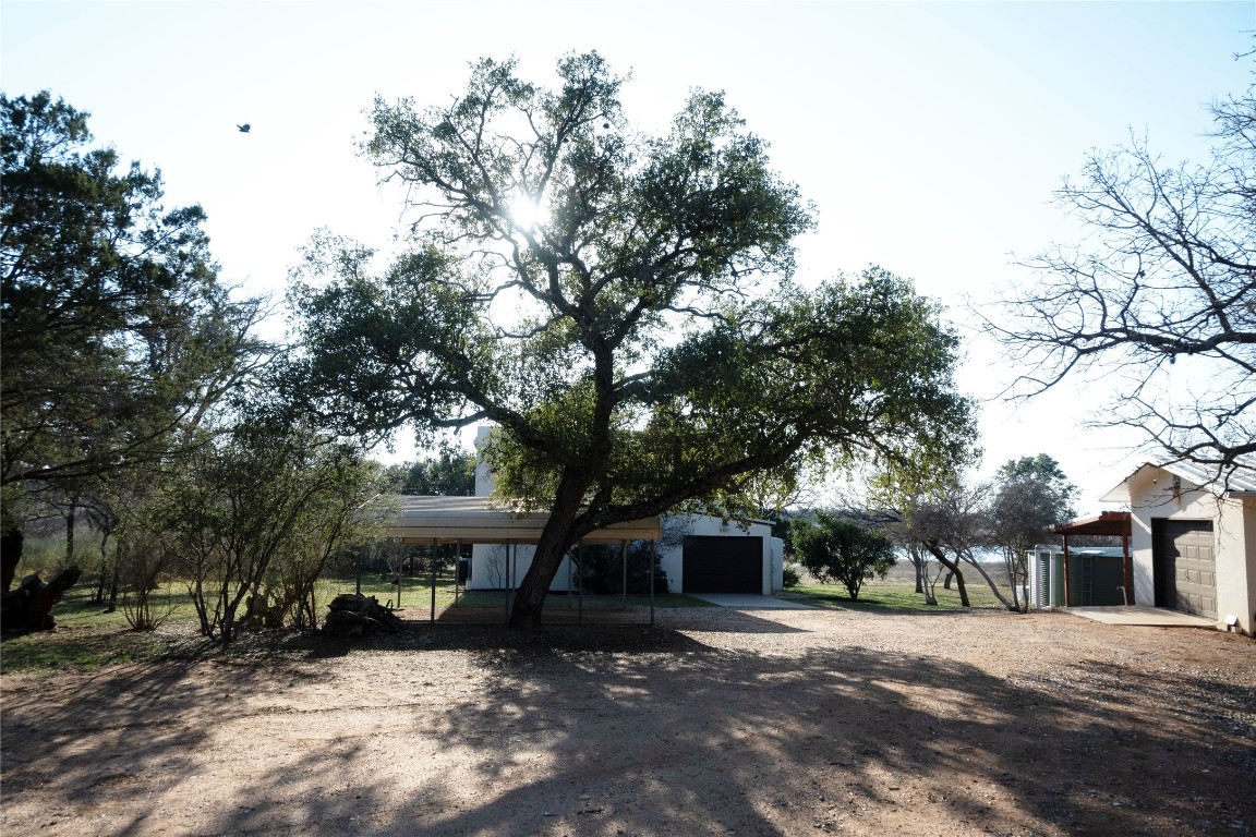5100 Farm To Market Road 690 Burnet, TX 78611 - Photo 7 of 10 View of front facade featuring a carport, dirt driveway, and an outbuilding