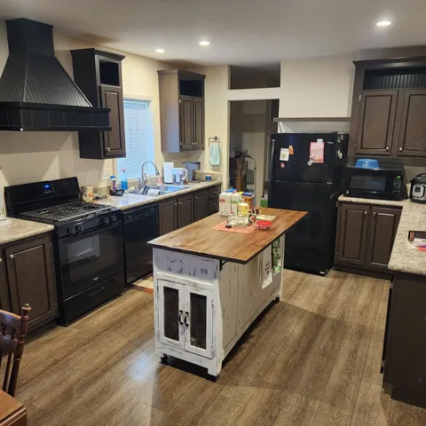 a kitchen with stainless steel appliances kitchen island granite countertop a stove a sink and a refrigerator