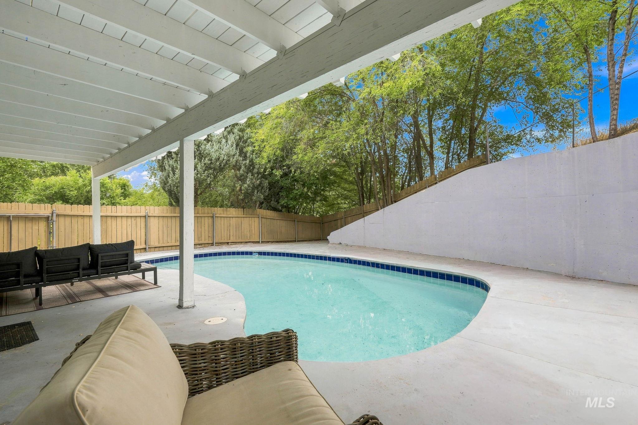 2442 West Hill Road Boise, ID 83702 - Photo 37 of 48 Covered patio with an irregular-shaped pool, concrete pool deck, and wood privacy fence