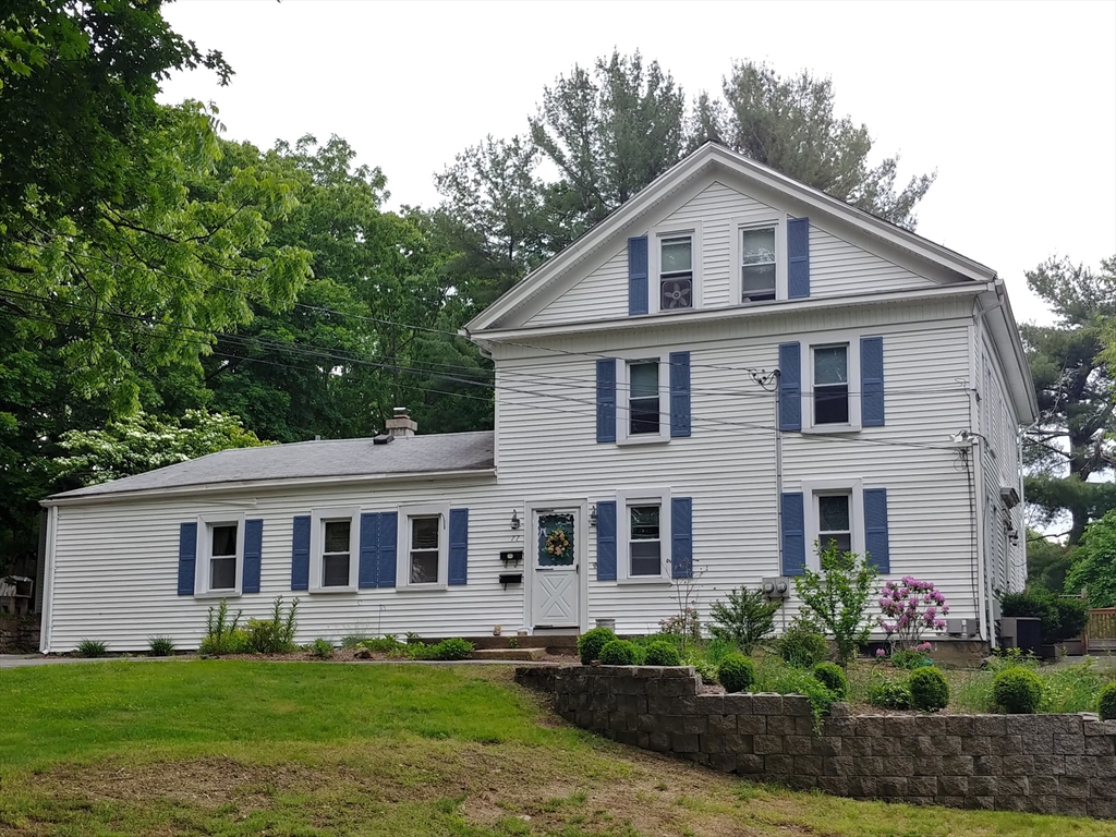 a front view of a house with a garden and trees